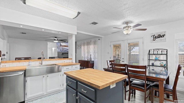 kitchen with wood counters, french doors, stainless steel dishwasher, sink, and white cabinets