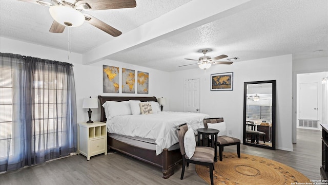 bedroom featuring beamed ceiling, ceiling fan, dark hardwood / wood-style flooring, and a textured ceiling