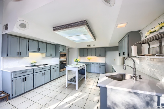 kitchen with backsplash, light tile patterned floors, sink, and appliances with stainless steel finishes