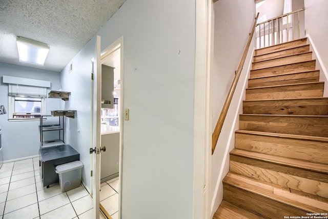 stairway with tile patterned flooring and a textured ceiling