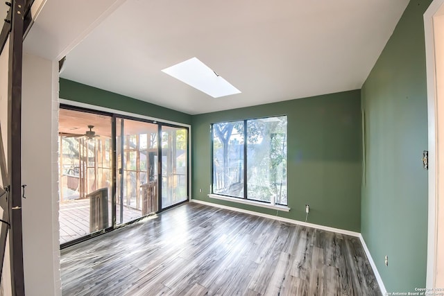 unfurnished room with hardwood / wood-style floors, a skylight, and ceiling fan