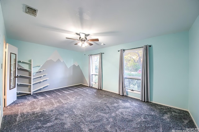 spare room with ceiling fan and dark colored carpet