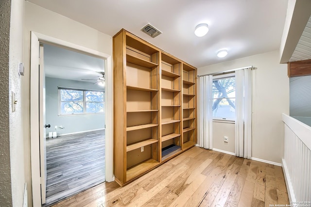 walk in closet with ceiling fan and light hardwood / wood-style flooring