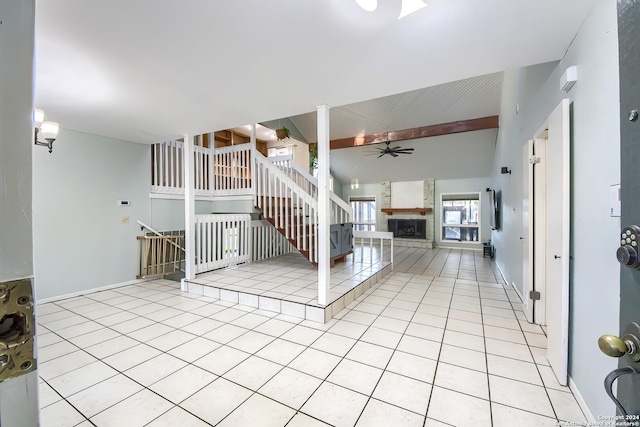 interior space with a stone fireplace, ceiling fan, and light tile patterned flooring