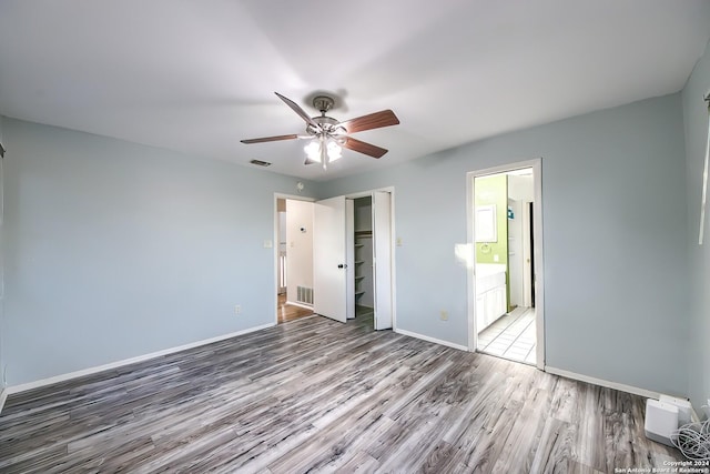 unfurnished bedroom with hardwood / wood-style floors, connected bathroom, a closet, and ceiling fan