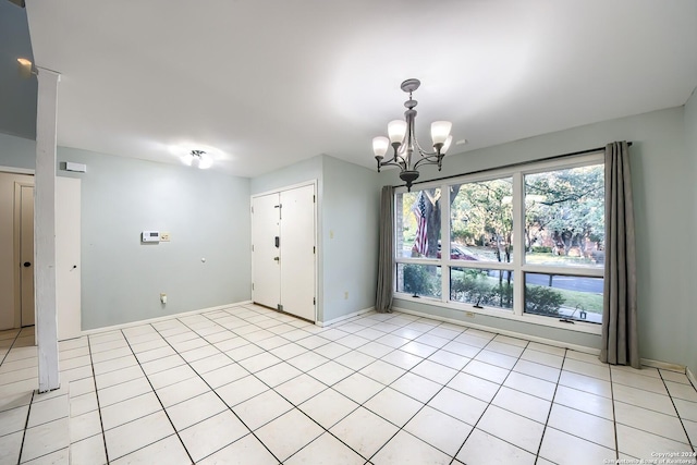 tiled spare room with an inviting chandelier and a healthy amount of sunlight