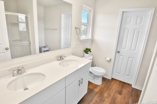 bathroom featuring wood-type flooring, vanity, toilet, and walk in shower