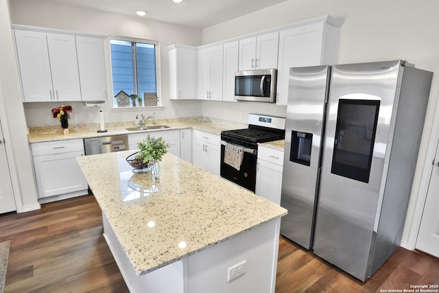 kitchen featuring appliances with stainless steel finishes, a center island, white cabinetry, and light stone counters