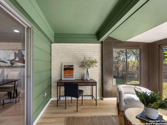 home office featuring light wood-type flooring and wooden walls