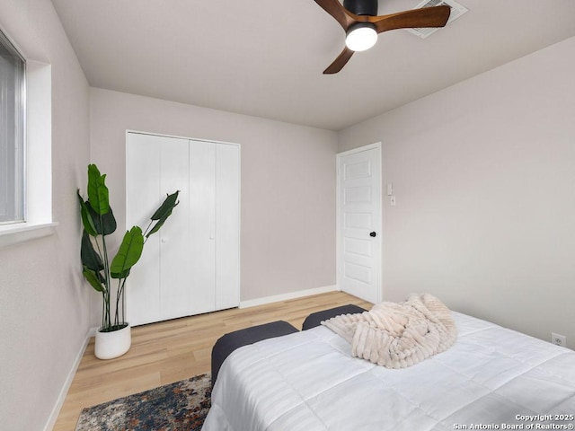 bedroom with ceiling fan, light hardwood / wood-style floors, and a closet