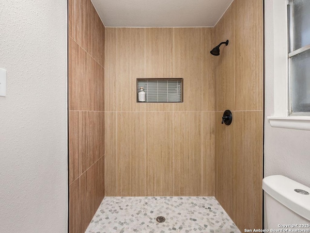 bathroom with a tile shower and toilet