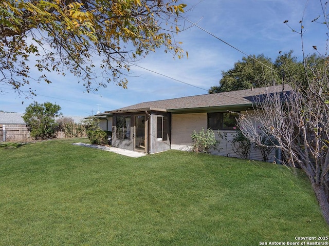 back of property with a sunroom and a yard