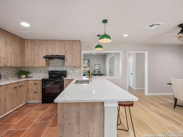 kitchen featuring a breakfast bar, ventilation hood, sink, decorative light fixtures, and black electric range oven