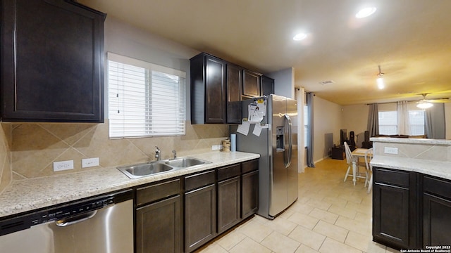 kitchen featuring appliances with stainless steel finishes, backsplash, dark brown cabinets, sink, and light tile patterned floors