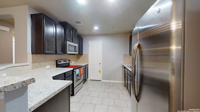 kitchen with decorative backsplash, appliances with stainless steel finishes, light stone countertops, and light tile patterned flooring