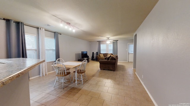 tiled dining space featuring track lighting and ceiling fan