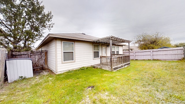 rear view of property featuring a yard, a pergola, and a deck