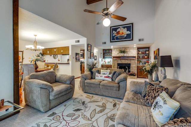 carpeted living room with built in shelves, a fireplace, a towering ceiling, and ceiling fan with notable chandelier