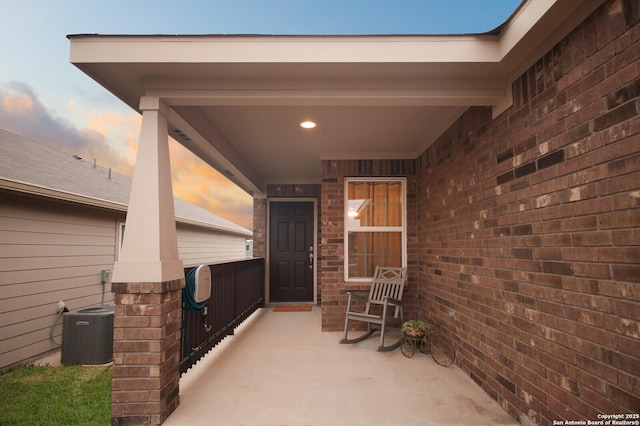 exterior entry at dusk featuring central AC and covered porch