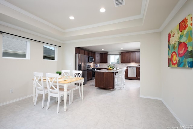 dining area featuring ornamental molding, sink, and a tray ceiling