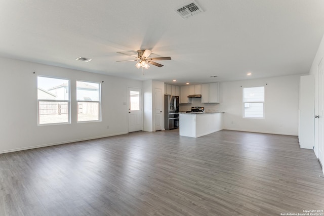 unfurnished living room with a wealth of natural light, ceiling fan, and light wood-type flooring