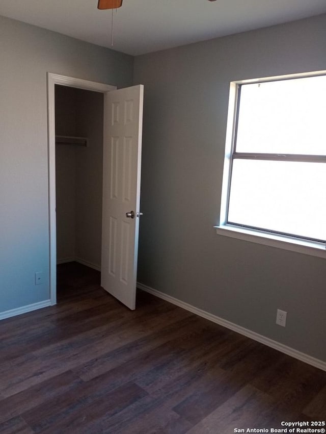 unfurnished bedroom with ceiling fan, dark wood-type flooring, and a closet