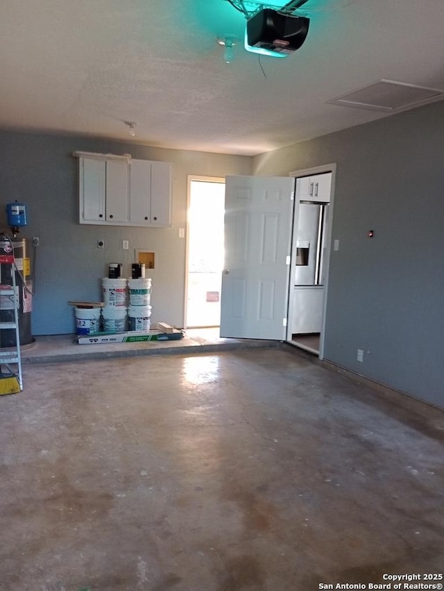 garage featuring stainless steel refrigerator with ice dispenser and a garage door opener