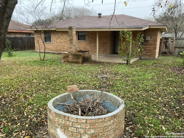 back of house with a lawn, a patio area, and an outdoor fire pit