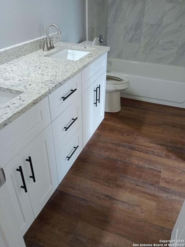 full bathroom with wood-type flooring, vanity, toilet, and tiled shower / bath