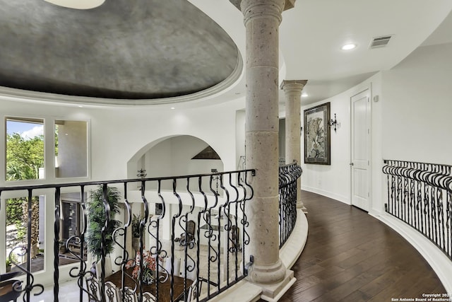 corridor with hardwood / wood-style floors and decorative columns