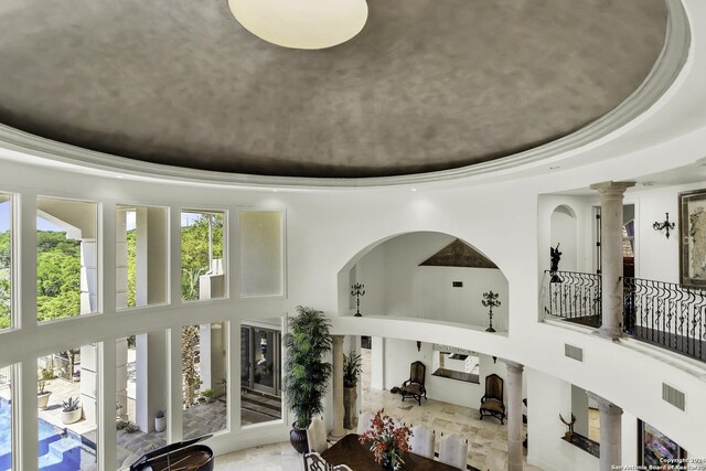 room details with a raised ceiling, crown molding, and ornate columns