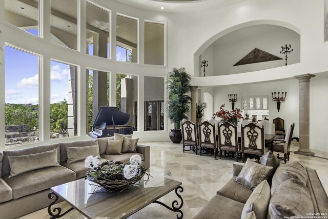 living room featuring a towering ceiling and decorative columns