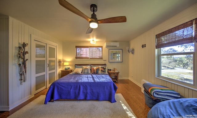 bedroom featuring ceiling fan, a wall mounted air conditioner, and hardwood / wood-style floors