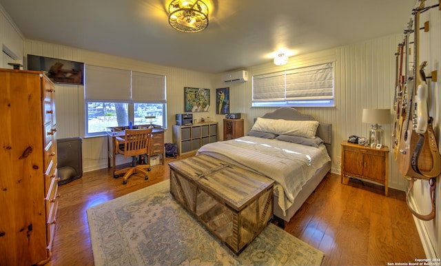 bedroom with a wall mounted AC and dark hardwood / wood-style floors