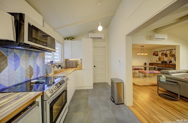 kitchen with white cabinets, a wall mounted air conditioner, pendant lighting, and stainless steel appliances