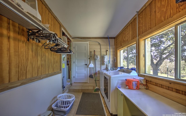 clothes washing area with independent washer and dryer, wooden walls, and light tile patterned floors