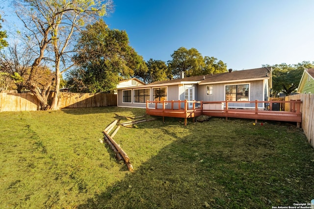 back of house with a lawn, a sunroom, and a wooden deck