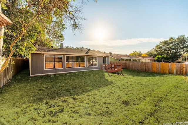 rear view of property featuring a deck and a lawn