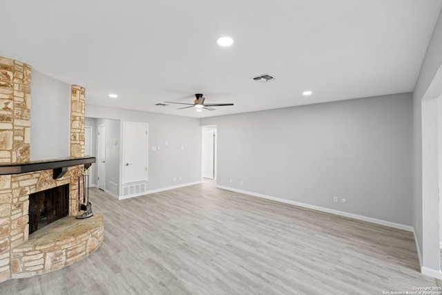 unfurnished living room with ceiling fan, a fireplace, and light wood-type flooring