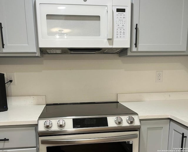 kitchen featuring stainless steel range with electric stovetop and white cabinets