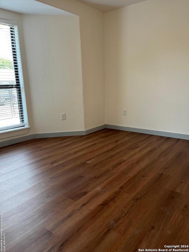 unfurnished room with dark wood-type flooring