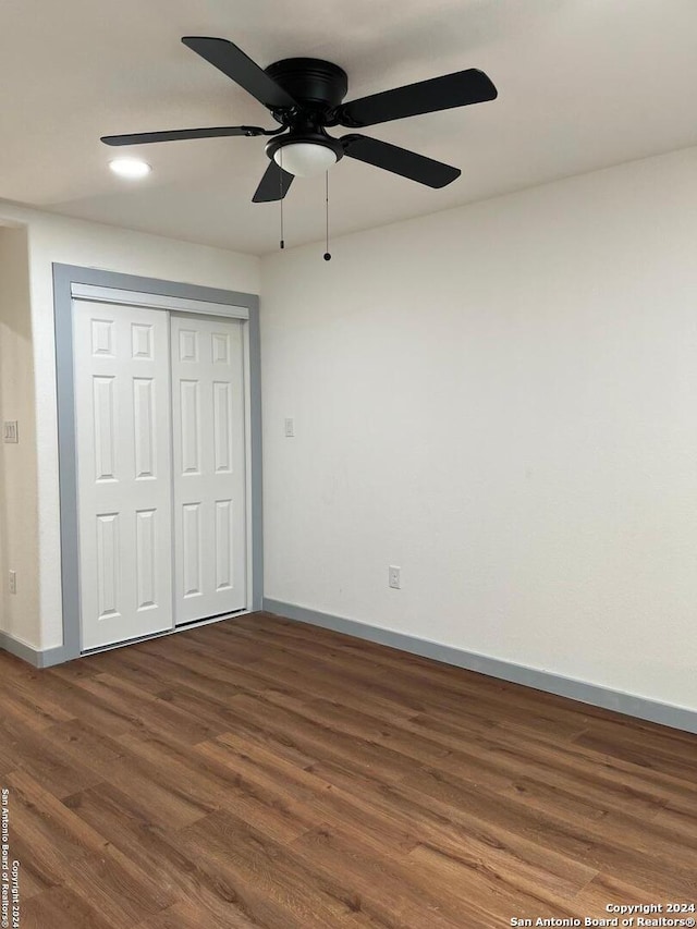 unfurnished bedroom featuring ceiling fan, dark hardwood / wood-style flooring, and a closet