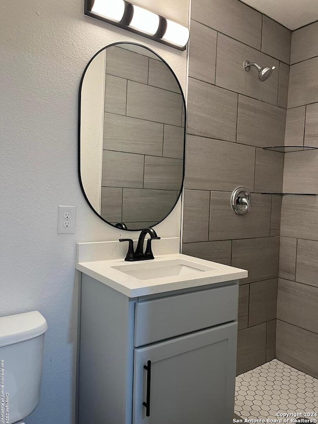 bathroom featuring vanity, toilet, and tiled shower