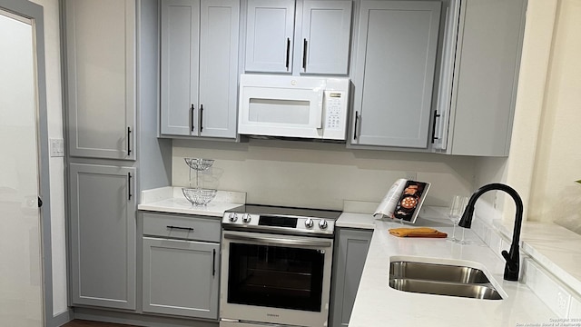 kitchen featuring stainless steel range with electric stovetop, gray cabinetry, and sink