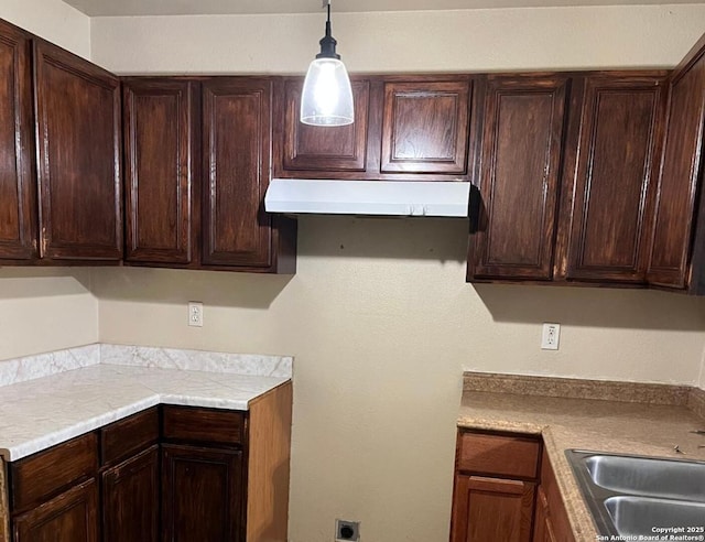 kitchen with decorative light fixtures, dark brown cabinets, and sink