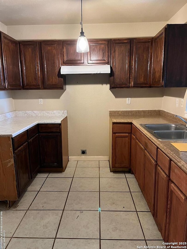 kitchen featuring decorative light fixtures, dark brown cabinetry, light tile patterned floors, and sink