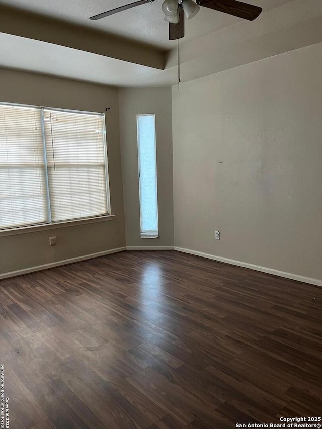 empty room with dark hardwood / wood-style floors, a raised ceiling, and ceiling fan