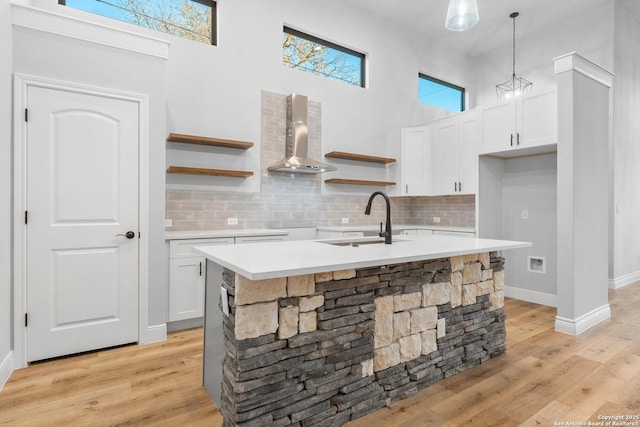 kitchen featuring sink, white cabinetry, hanging light fixtures, and a kitchen island with sink