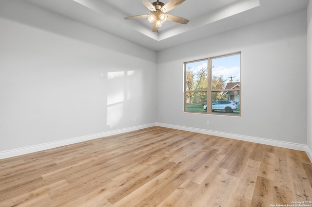 spare room featuring ceiling fan, light hardwood / wood-style flooring, and a tray ceiling