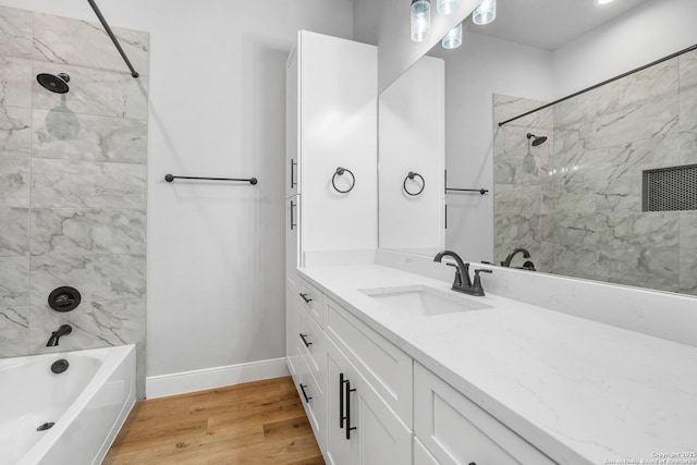 bathroom with vanity, hardwood / wood-style flooring, and tiled shower / bath